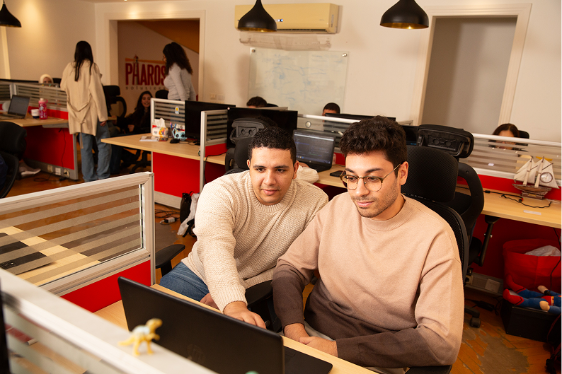 photograph of two software developers working together at Pharos Solutions office in front of a laptop